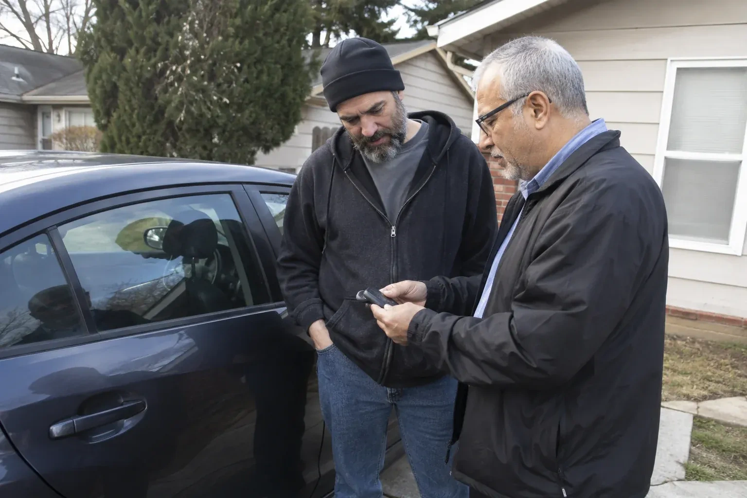 Two adults discussing a key fob beside a parked car. — Car Lockout Service, Wasaga Beach