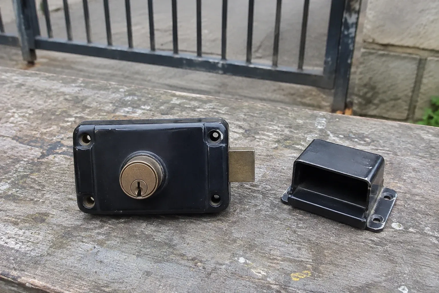 Detached rim gate lock and separate box keeper on an outdoor workbench. — Gate & Building Entry Locks, Wasaga Beach