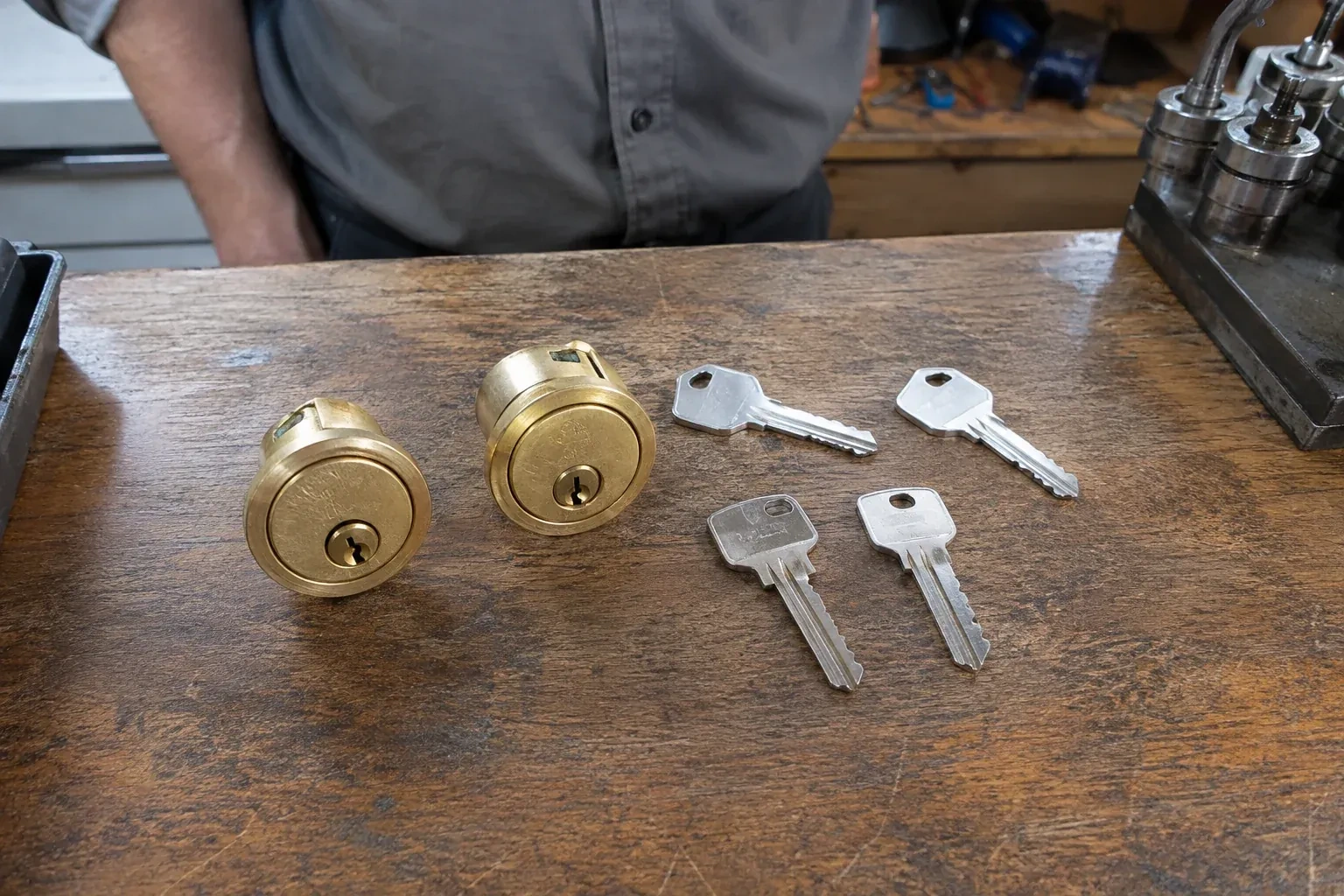 Two detached brass lock cylinders and four house keys on a wooden counter. — Lock Rekeying, Wasaga Beach